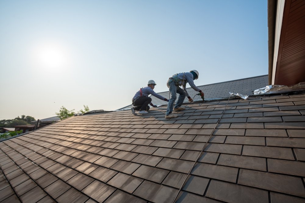 Roofing crew applying underlayment and flashing during residential install